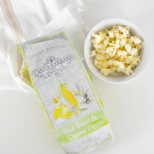 Santa Barbara Popcorn Co. sea salt and olive oil artisan popcorn bag next to white bowl of popcorn