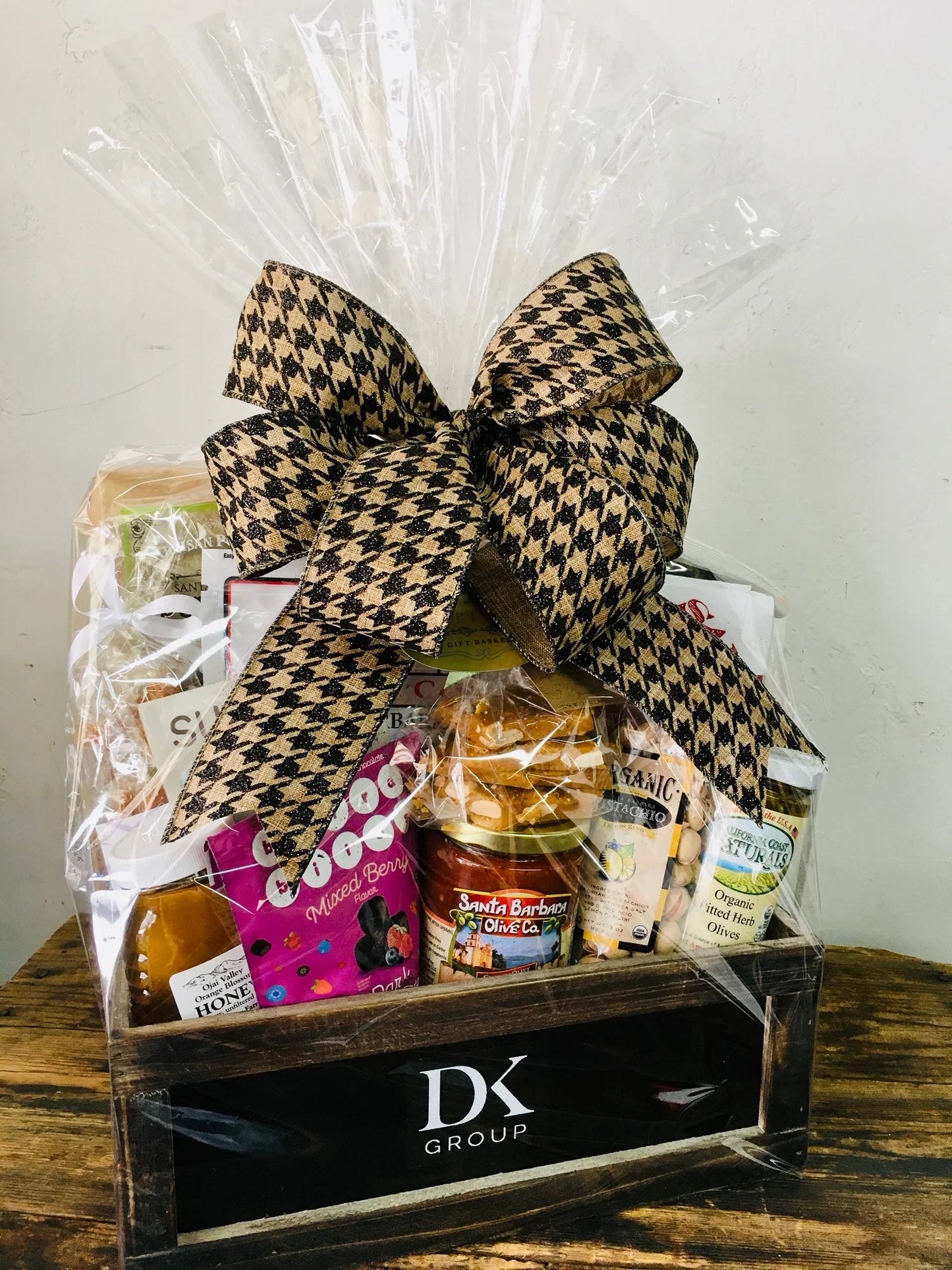 DK Group wooden gift basket with gourmet snacks wrapped in clear cellophane with houndstooth bow