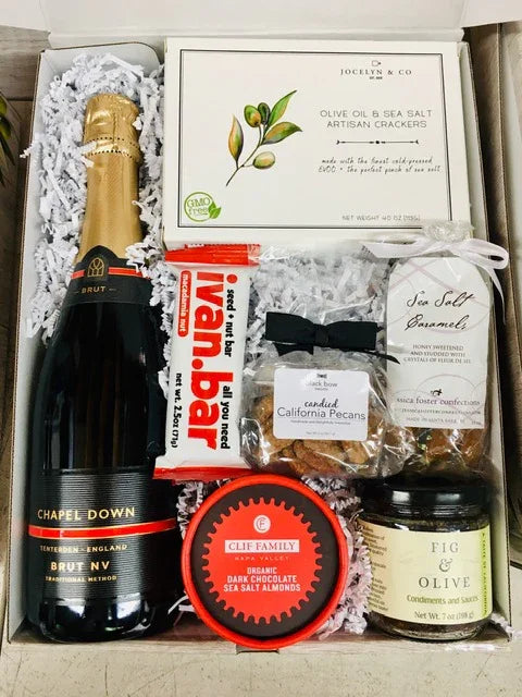 Gift box with Chapel Down Brut NV sparkling wine, olive oil sea salt crackers, Ivan Bar nut bar, candied pecans, sea salt caramels, dark chocolate almonds, and fig & olive condiments